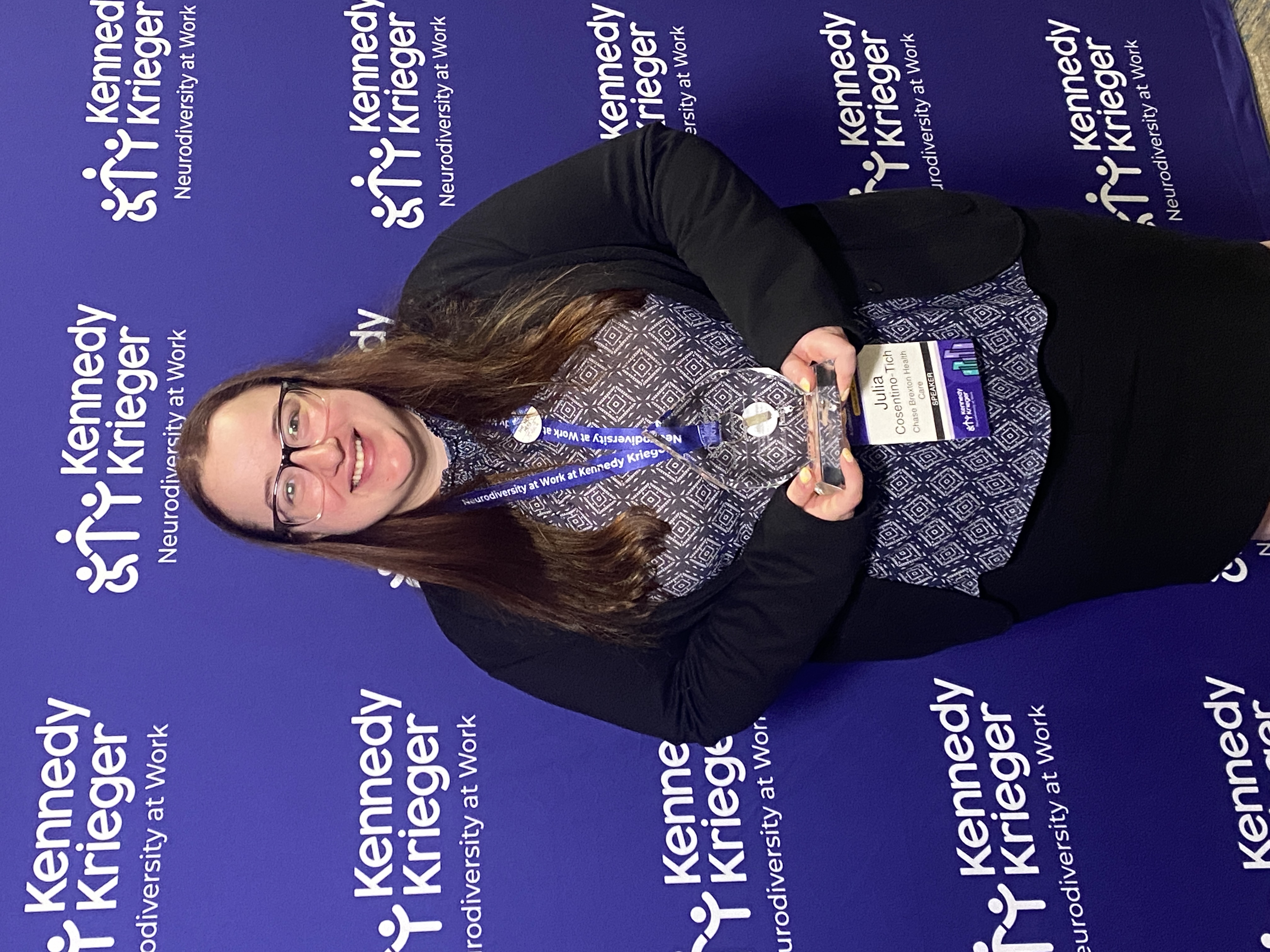 Julia Cosentino-Tich smiling with award in front of purple background