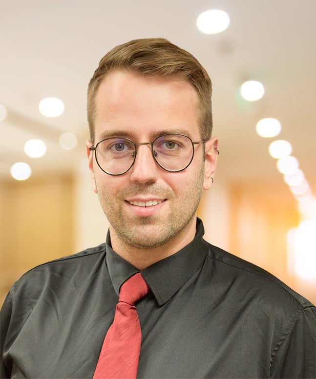 Photo for Dr. Dammann, white, short blonde hair, grey shirt, and red tie