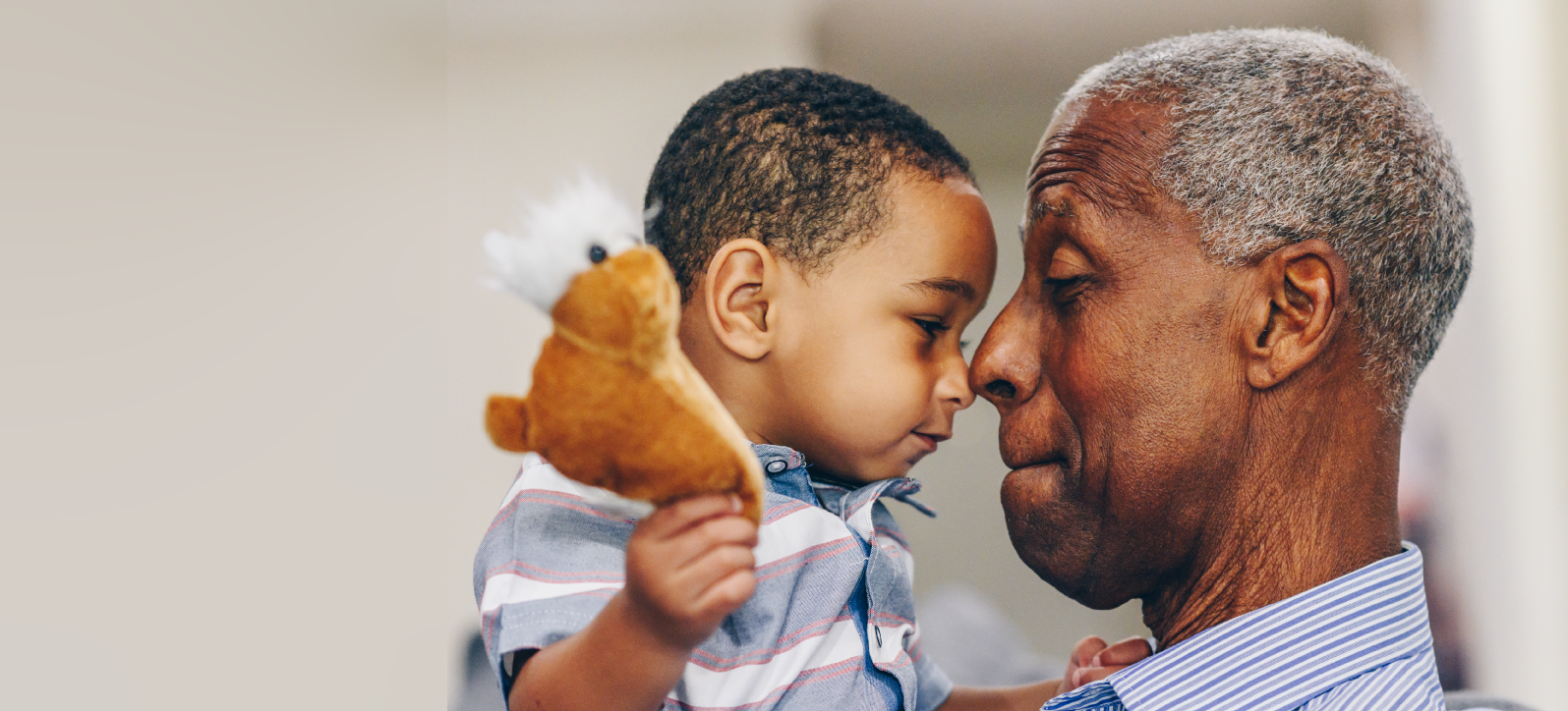 Grandfather holding grandchild, both nose to nose.
