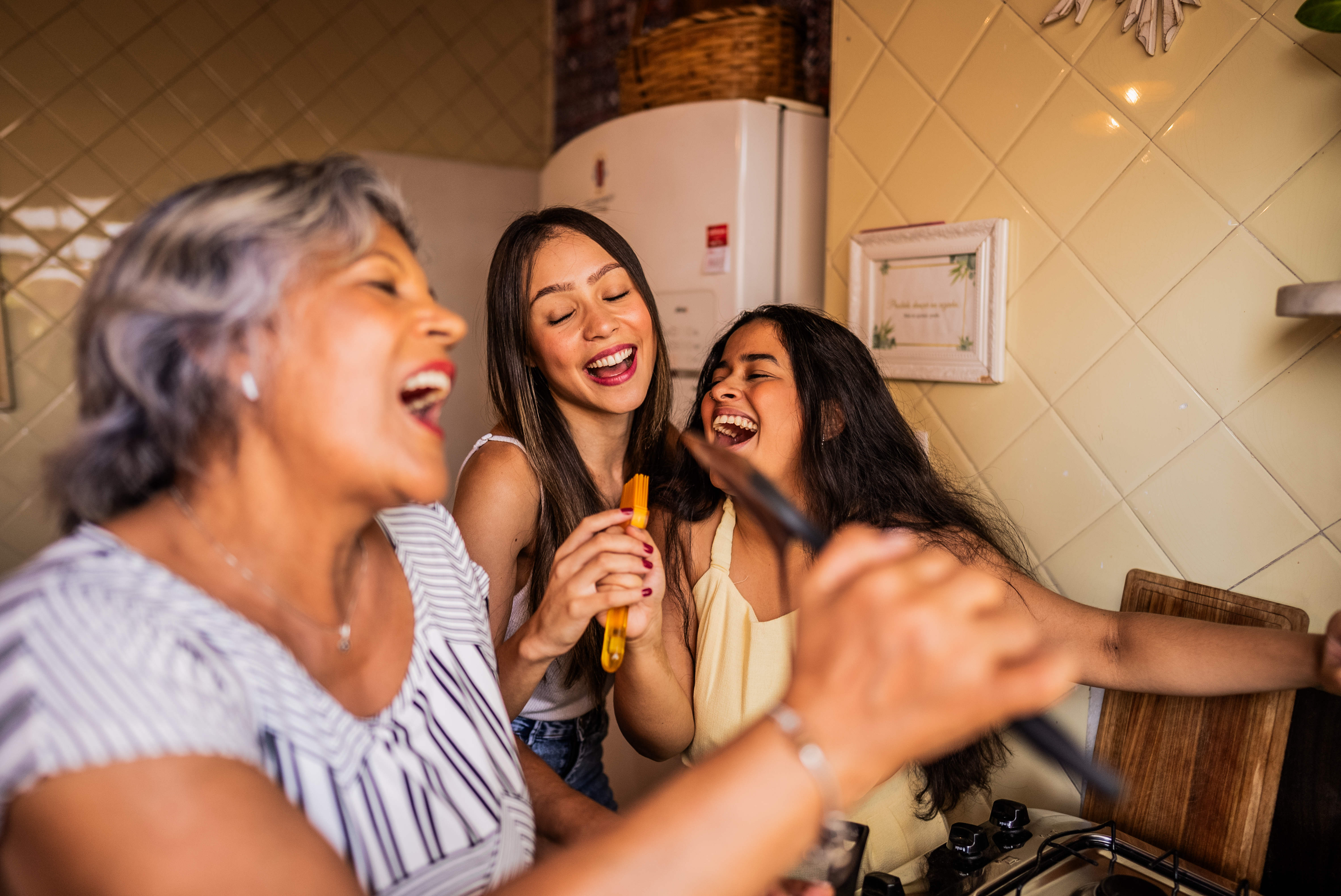 3 generations of women being silly and singing into ladles while cooking.