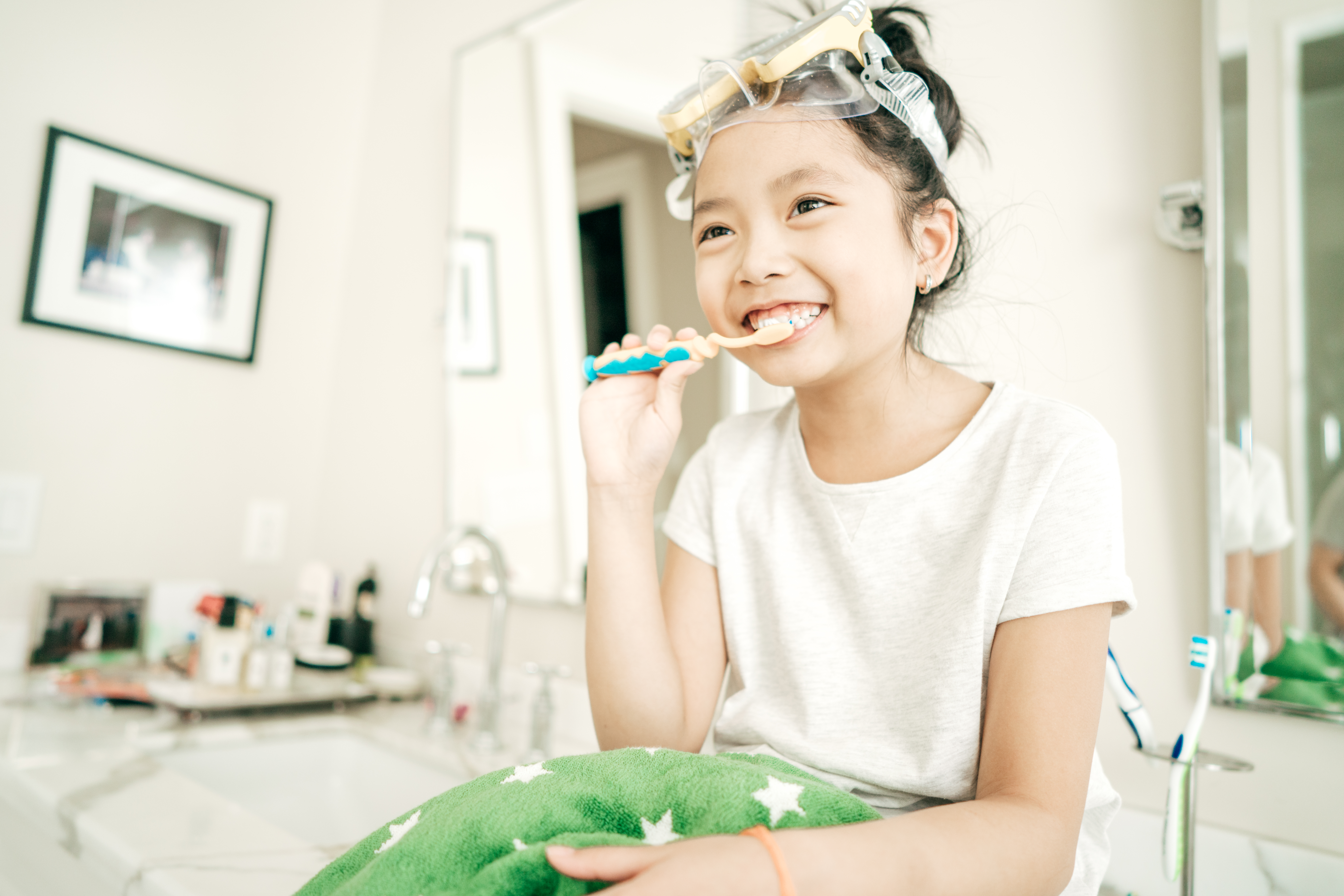 Child wearing goggles while brushing their teeth.