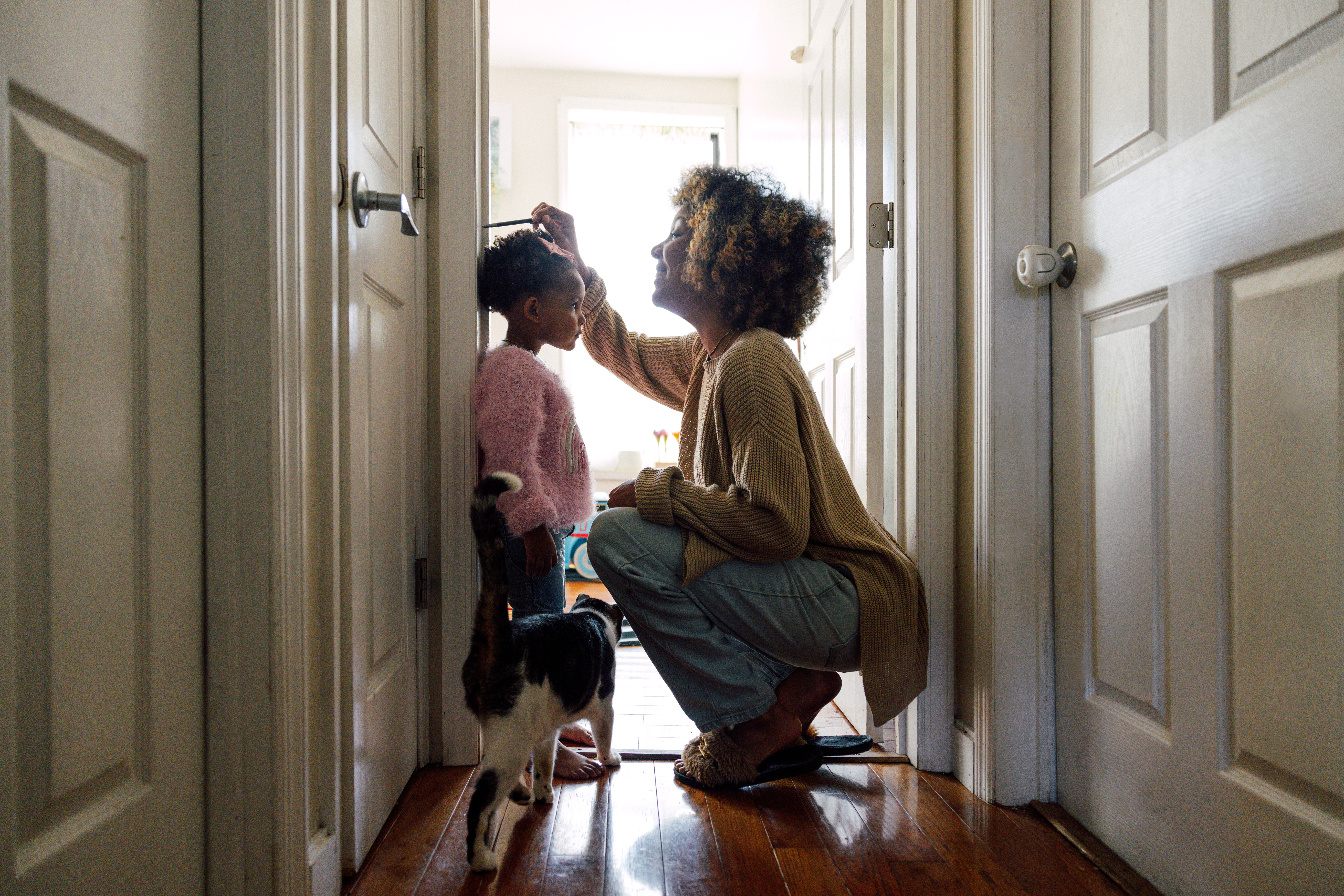 Mom measuring daughter's height by marking it on the door frame.