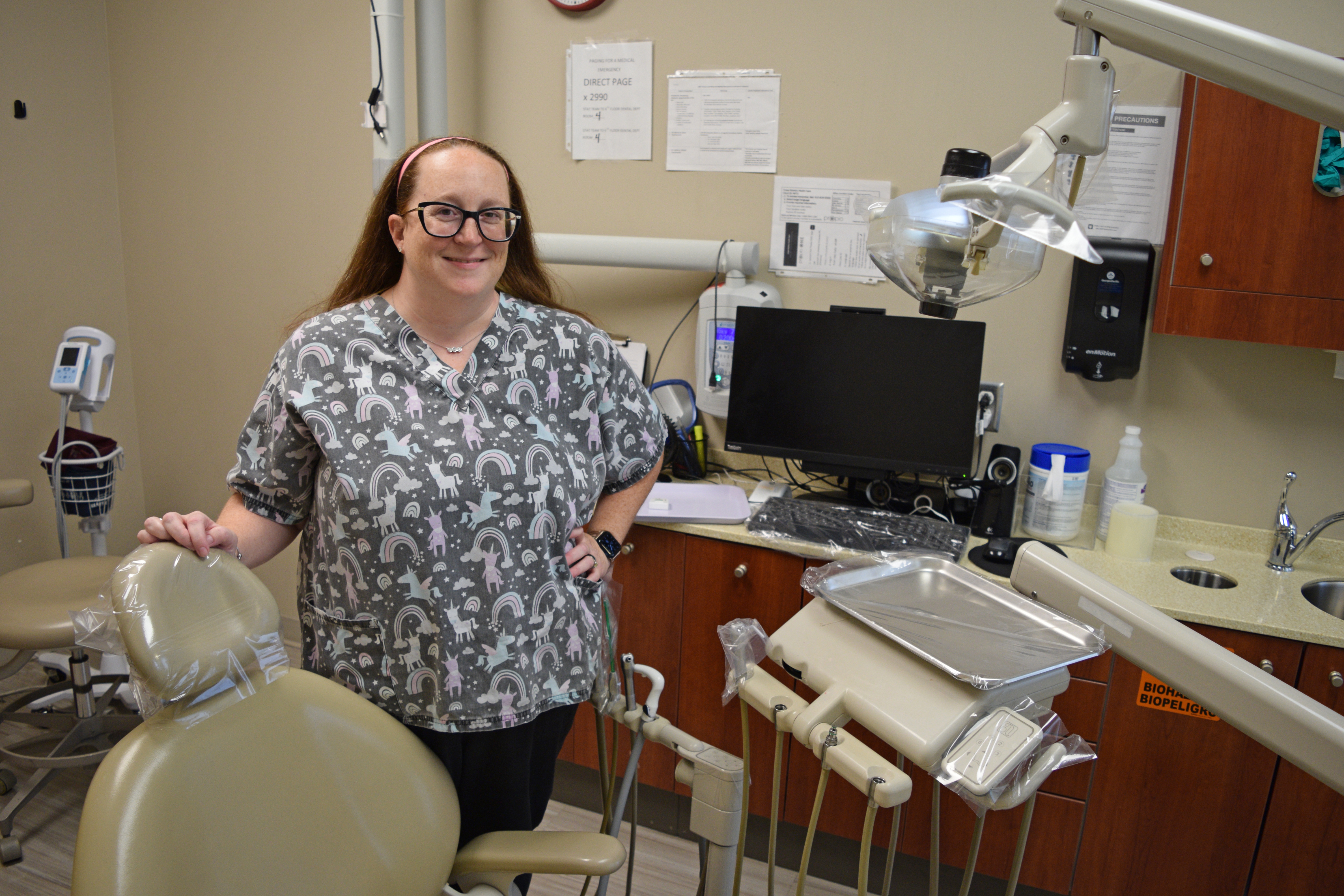 Karyn standing smiling by a dentist chair 