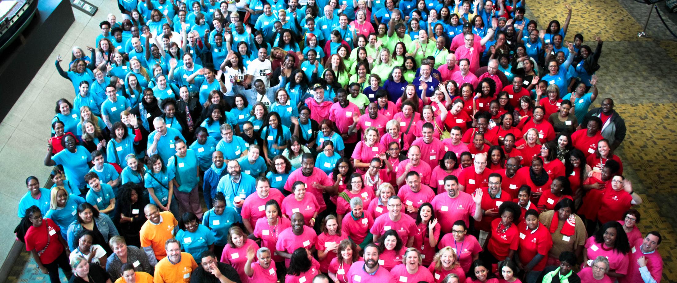Overhead view of full Chase Brexton staff in colorful blue, pink and orange t-shirts