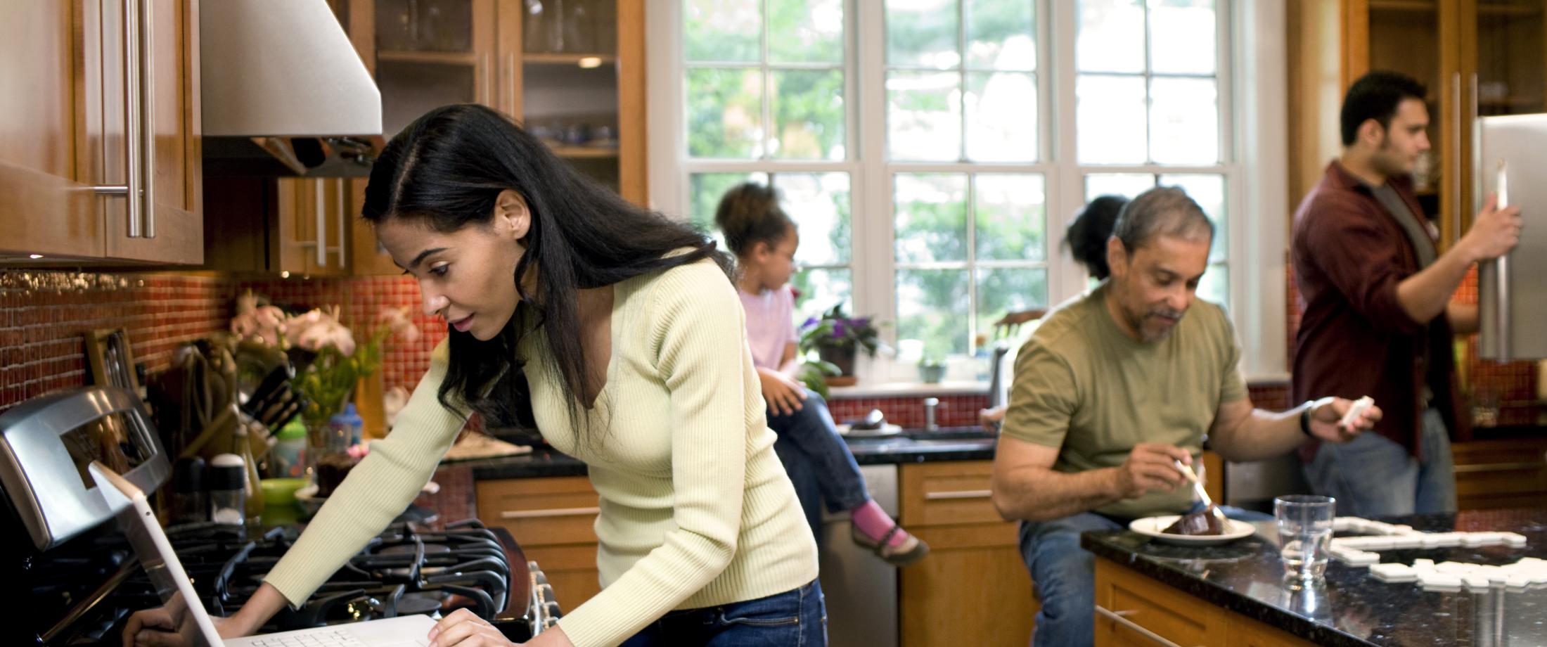 Family busy in a kitchen, one person on a computer.