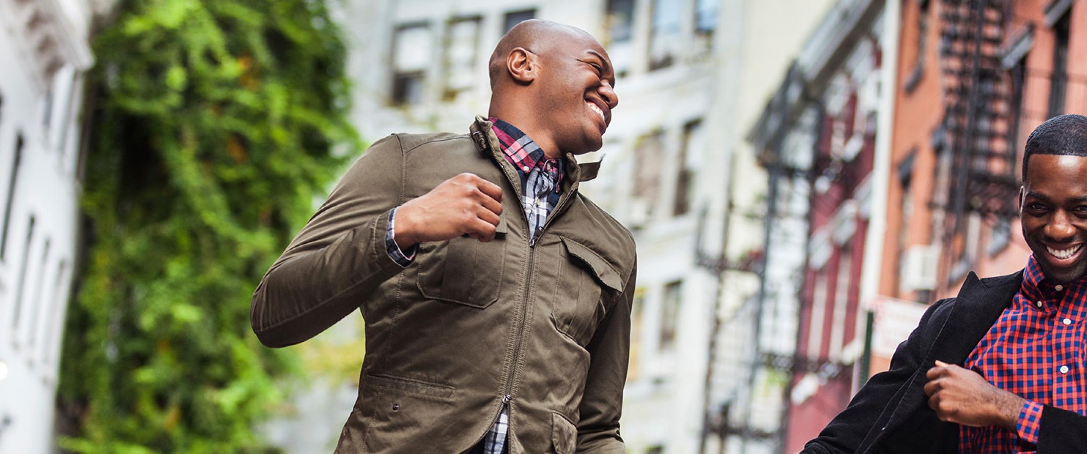 Two men smiling while walking together on a city street.