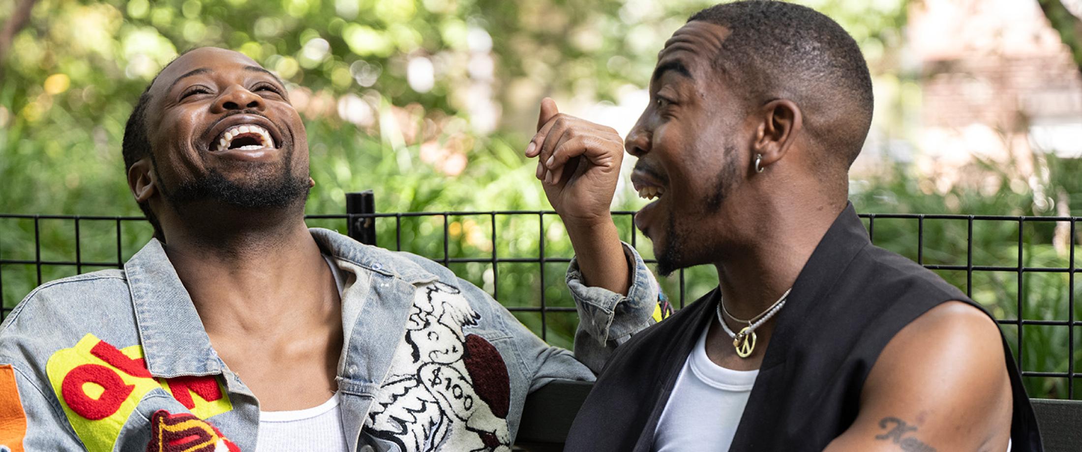 Two adults sitting on a park bench and laughing together.