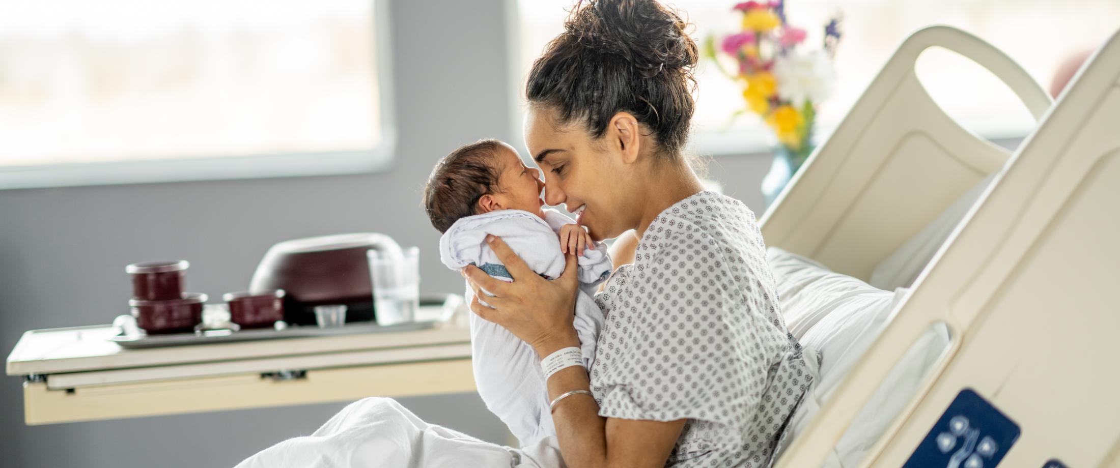 Mom holding baby nose to nose in hospital room.