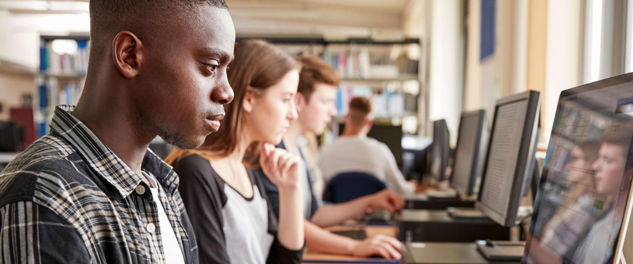 A line of students working on laptops and computers