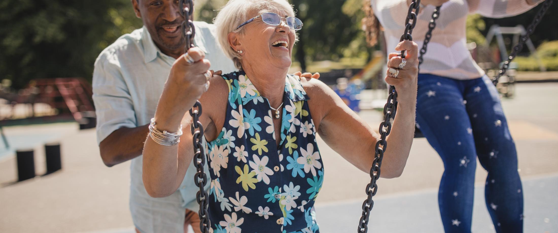 Older people swinging on playground swings.