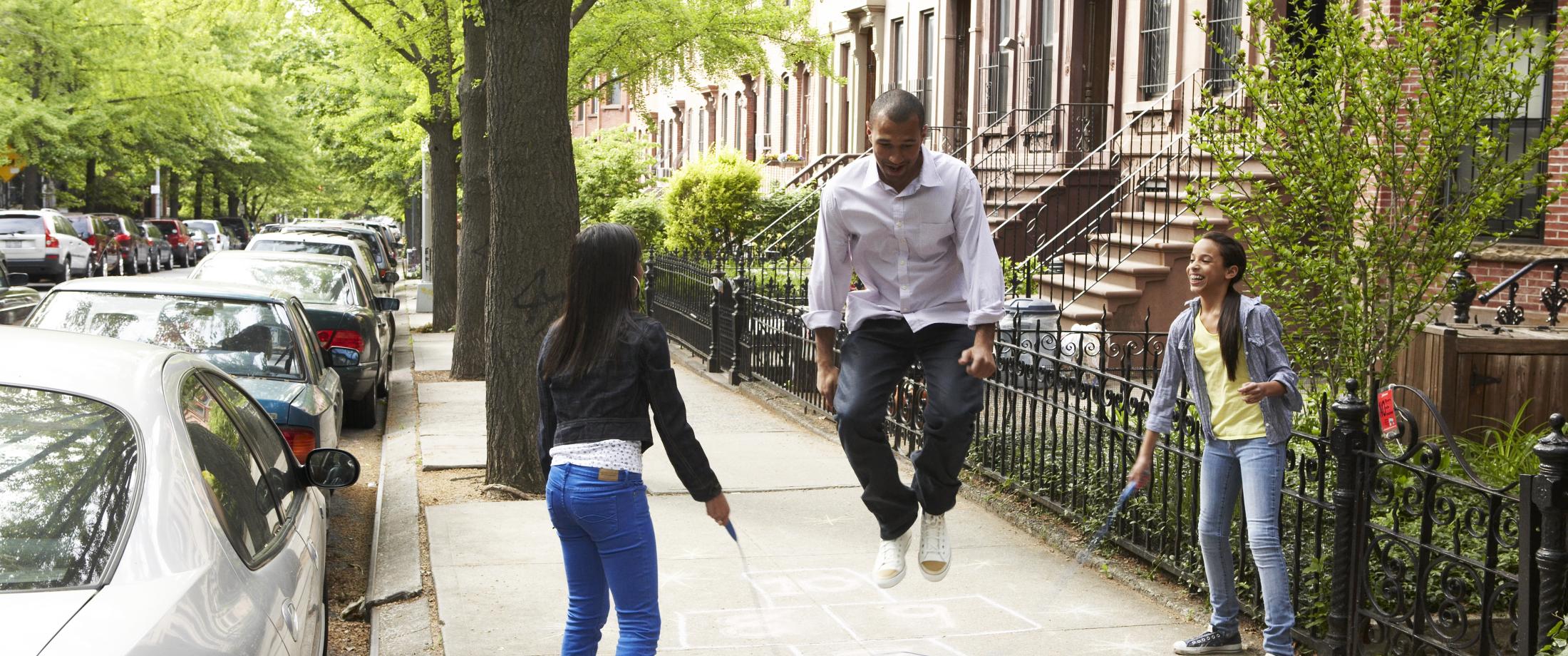 Dad jumping rope while daughters turn the rope.