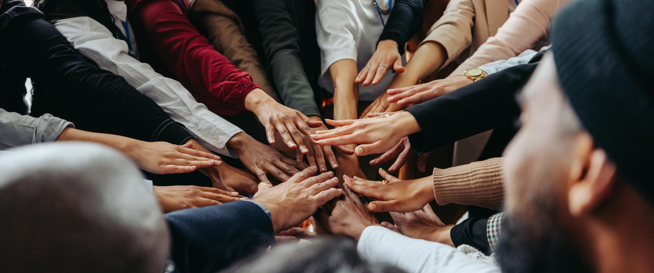 Team in a circle with hands in the center.