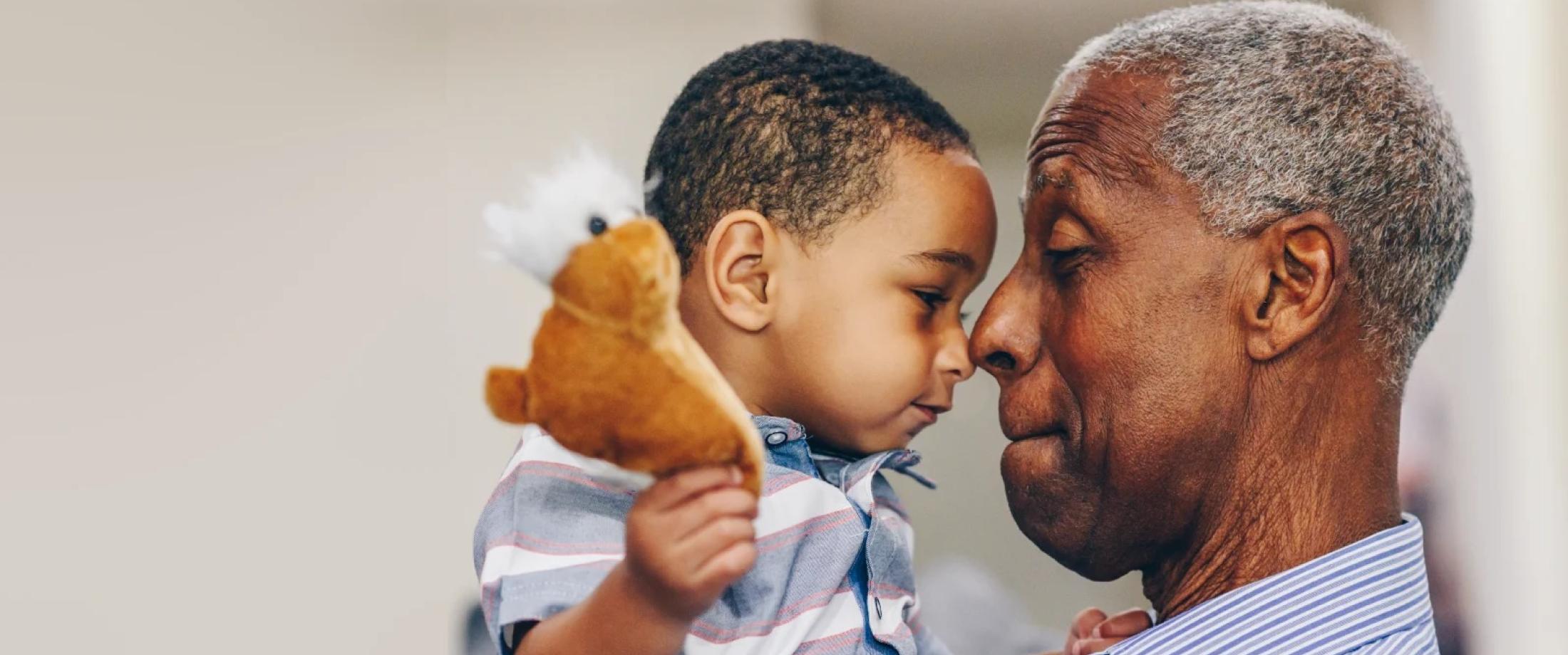 Elderly man kindly holds small boy
