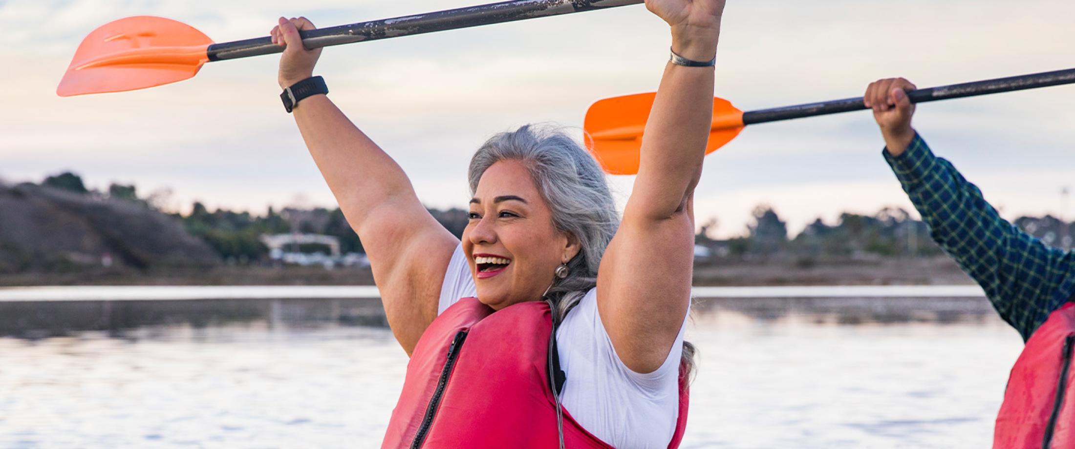 Two adults kayaking together on calm water.