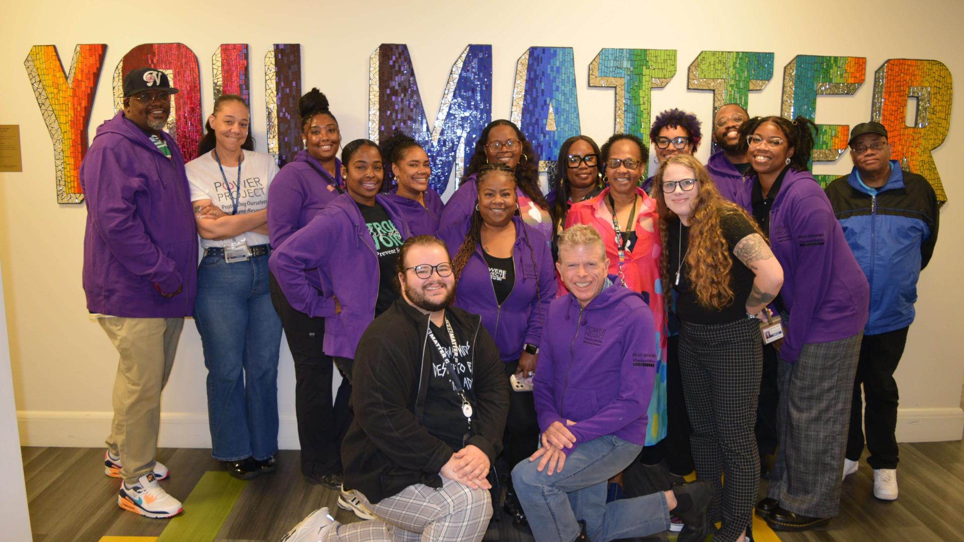 A group of smiling people standing in front of a large sign that says "You Matter"