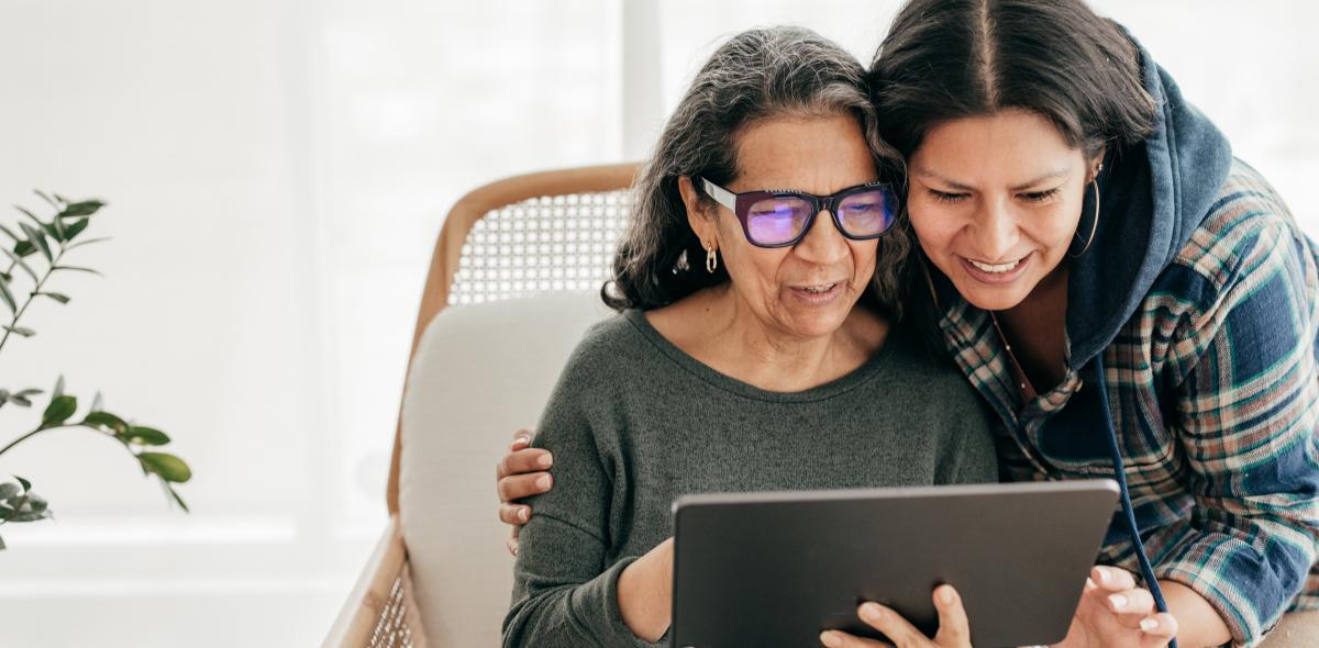 Older person looking at a tablet with daughter.