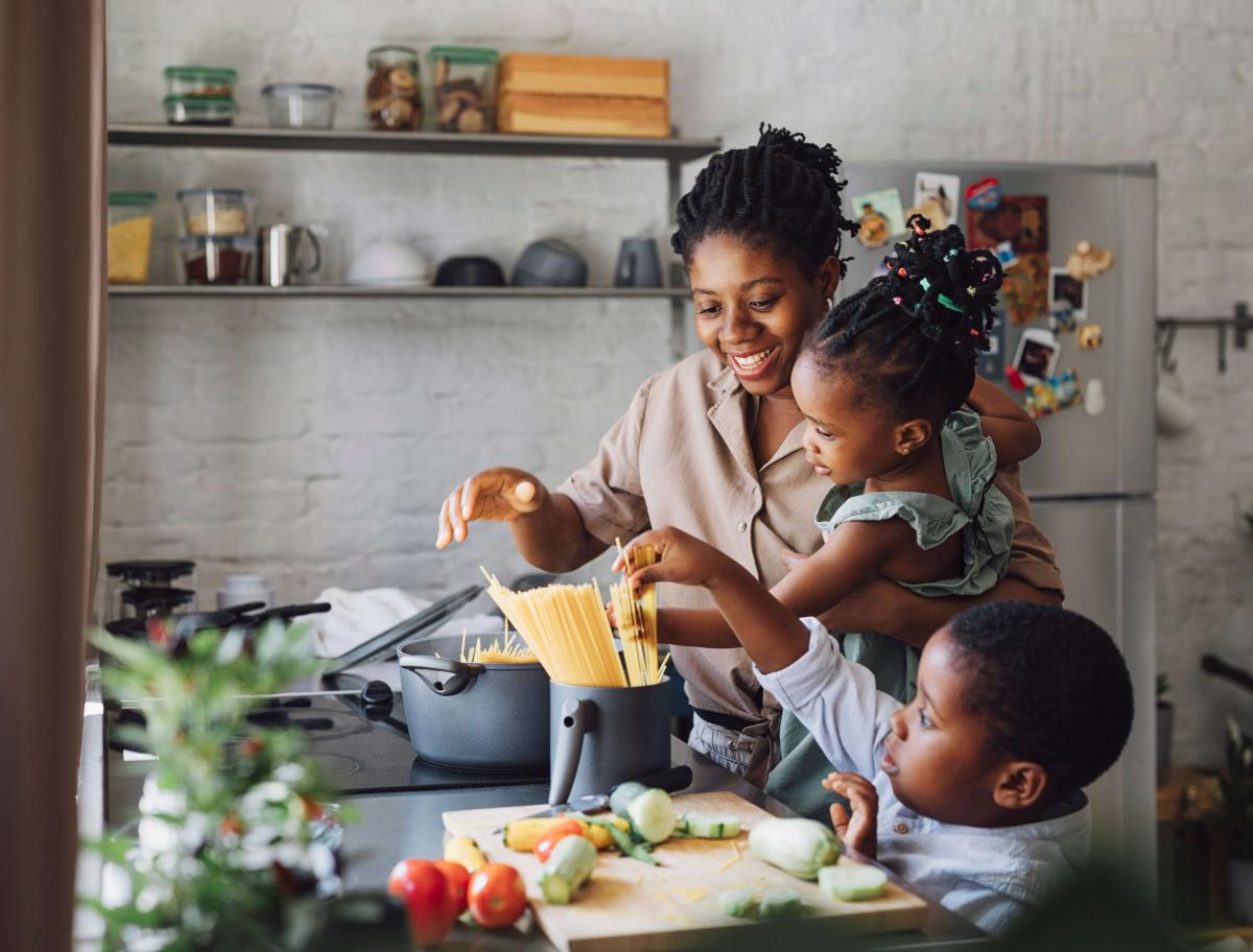 Mom cooking pasta along with toddler girl and small boy
