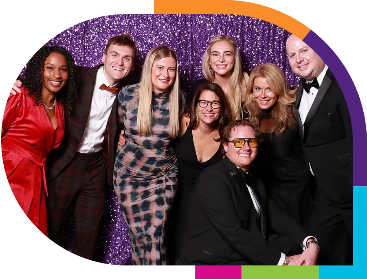 Group wearing black tie posing in front of a glittery purple wall