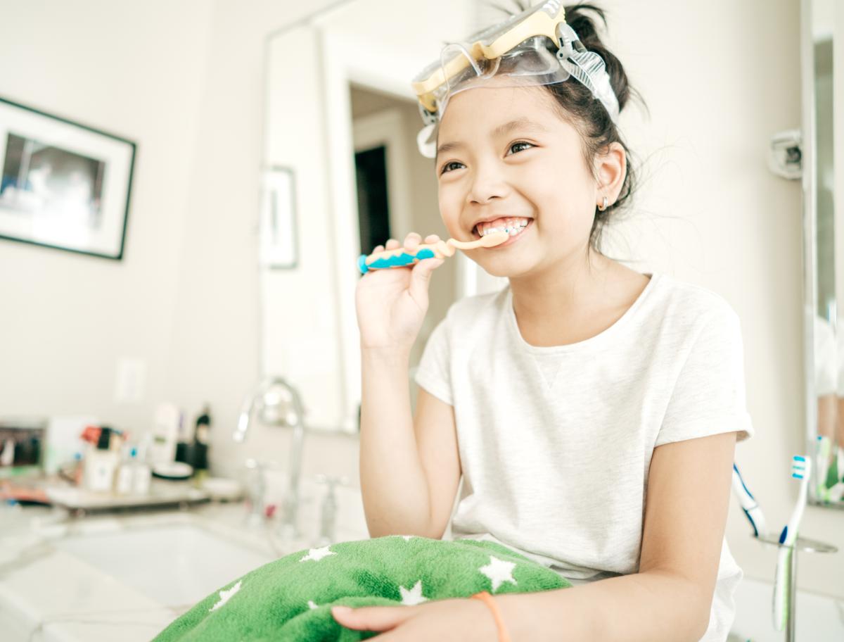 Child wearing goggles while brushing their teeth.
