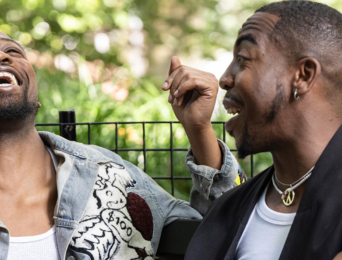 Two adults sitting on a park bench and laughing together.