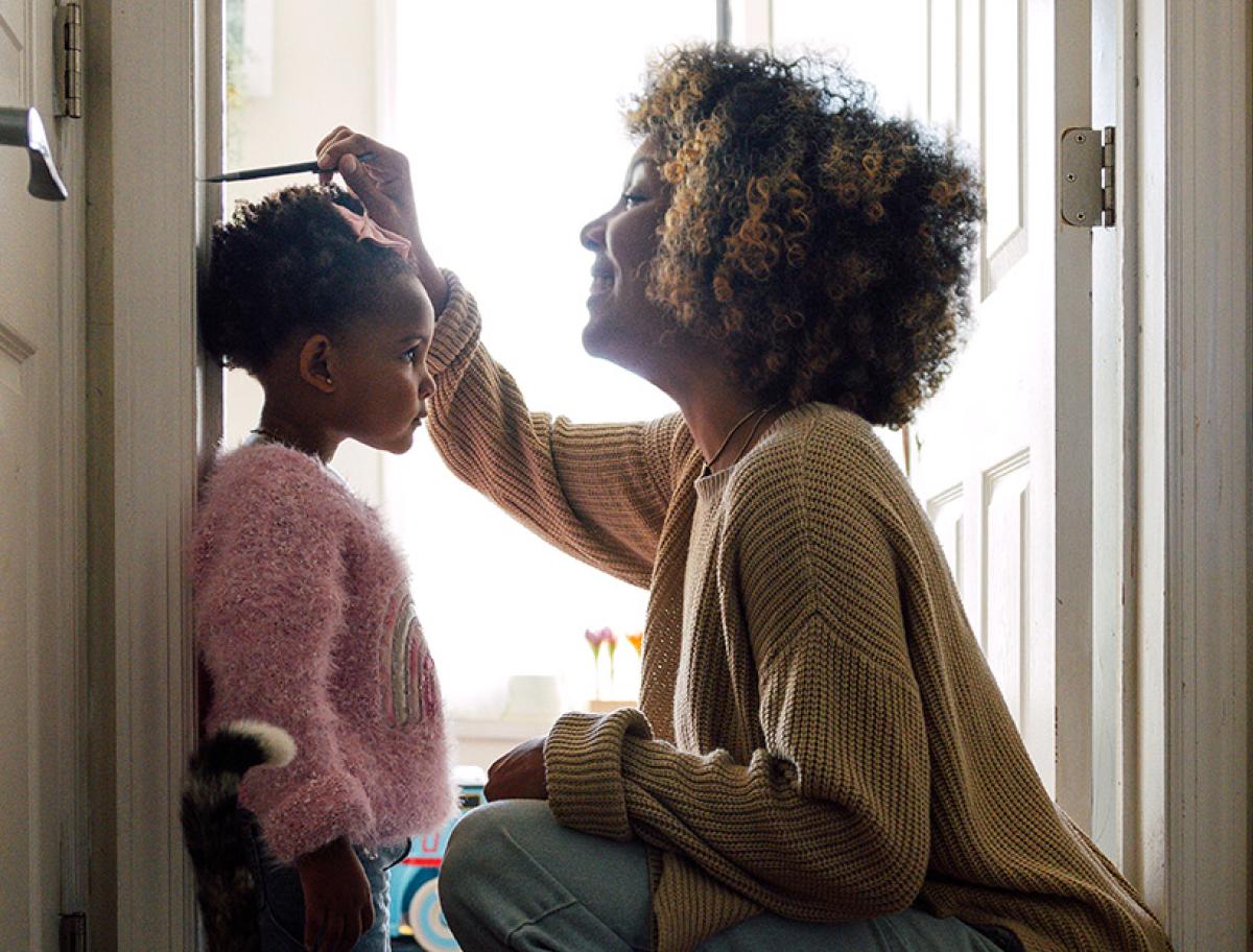 Adult measuring a young child’s height against a wall at home.