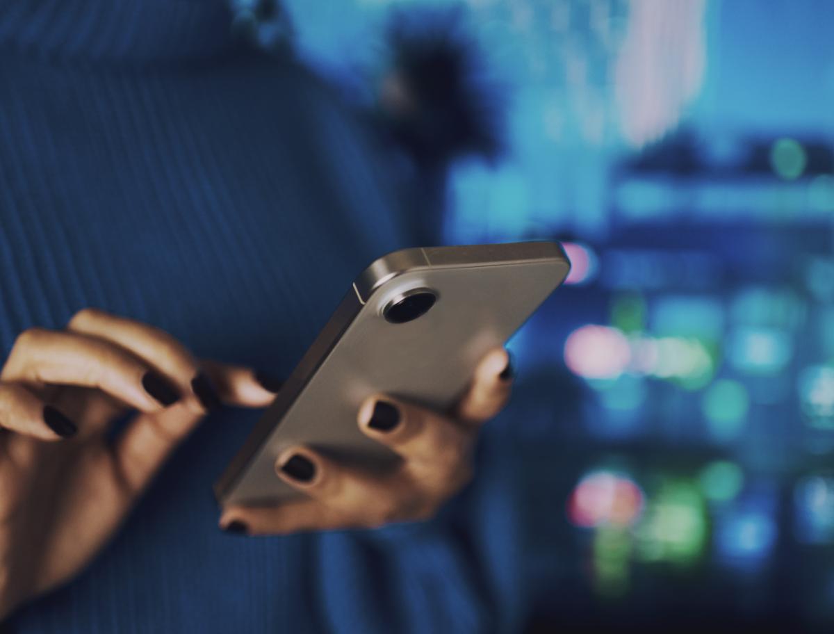 A person's hands holding a cell phone and dialing.