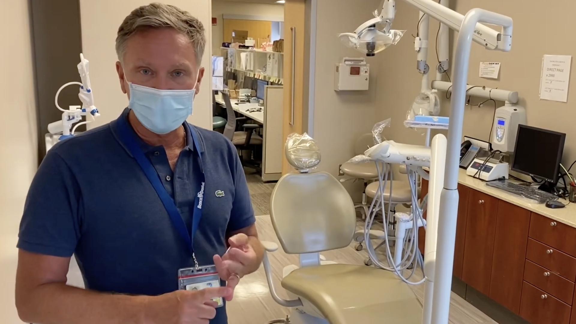 Dentist wearing face mask in front of a dental chair