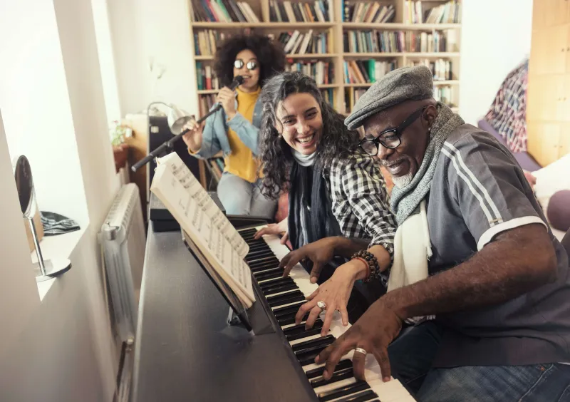 Three musicians playing the piano together and singing