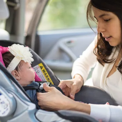 Mom putting her newborn baby into a car seat