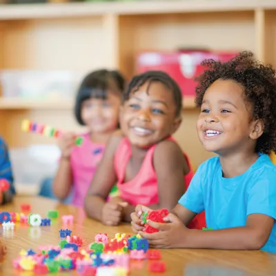Smiling children at a table with colorful toys
