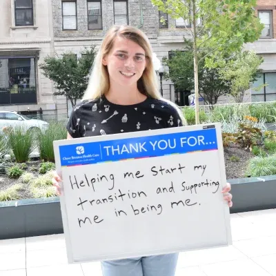 Person holding sign that says, "Thank you for helping me start my transition and supporting me in being me."