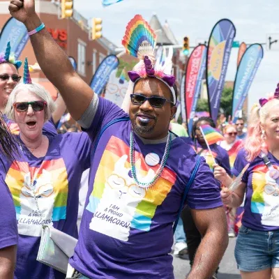 Man in purple shirt and unicorn headband during Pride walk