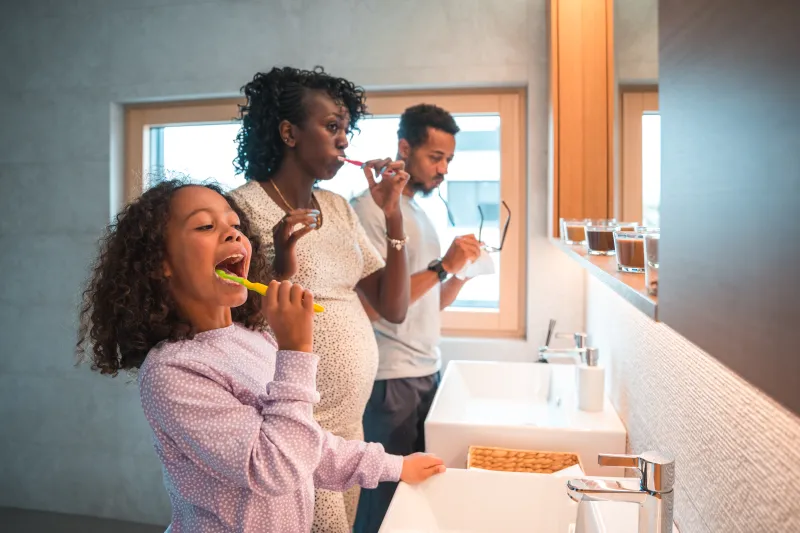 Family brushing teeth together, one member is pregnant.
