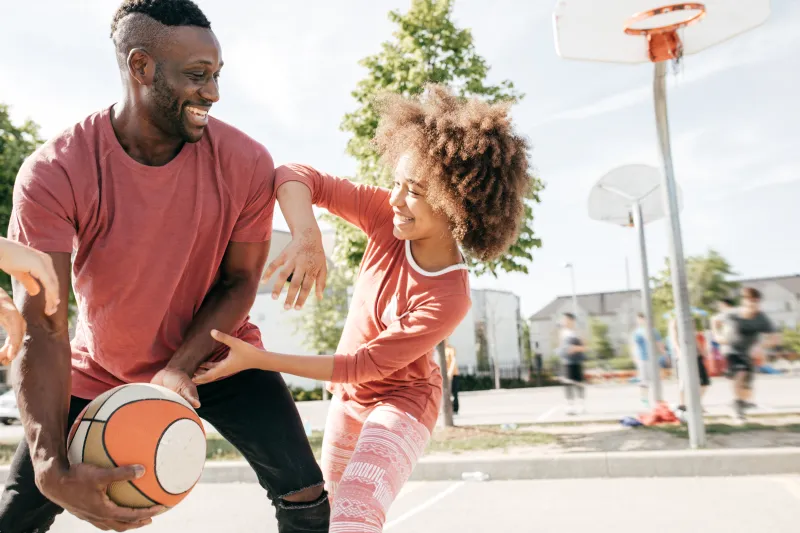 Dad and daughter play basketball.