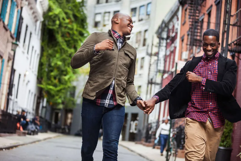 Two men smiling while walking together on a city street