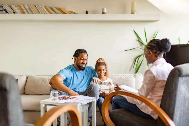 Dad and kid talking with therapist.